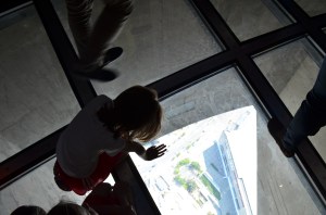 Abby looking down through the glass floor to the ground below. 
