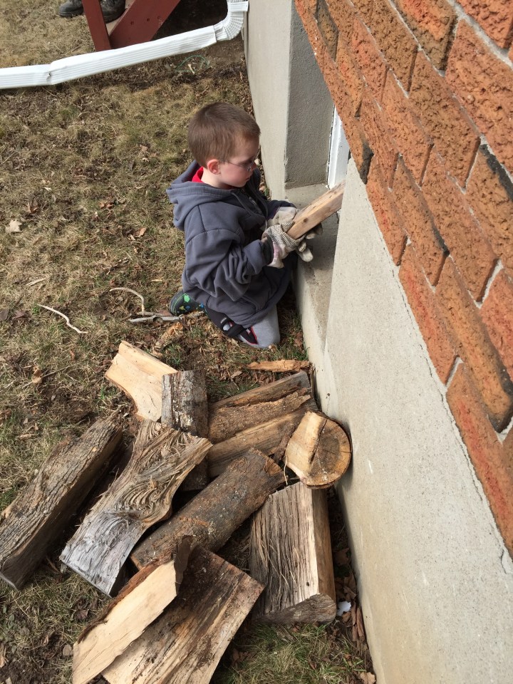 Aiden helping his Dad and Papa throw in the wood.