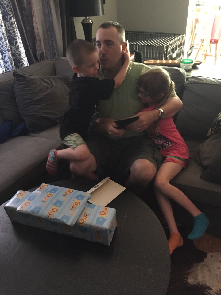 Peter getting hugs and kisses from Abby and Aiden after opening their gifts from school.