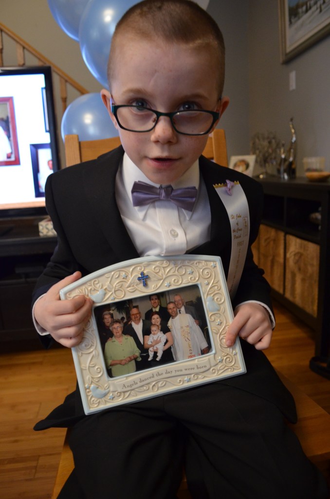 Aiden holding a picture from his baptism.